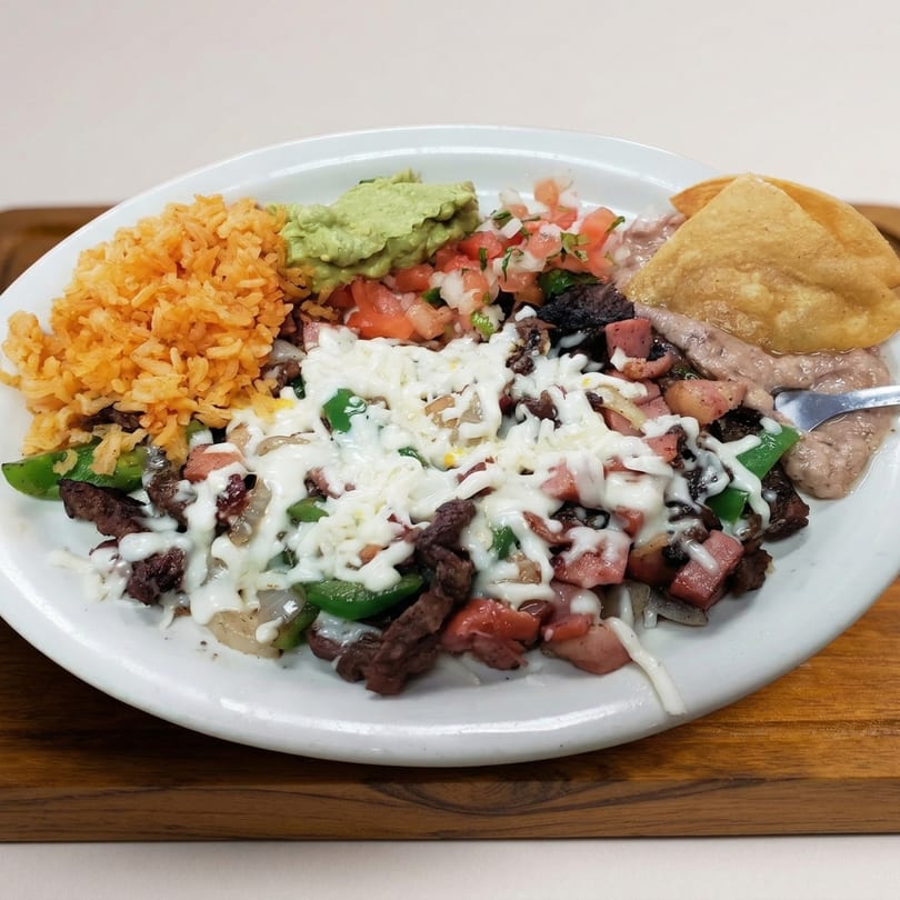 A white plate with steak, rice, beans, guacamole, pico de gallo, and tortillas.